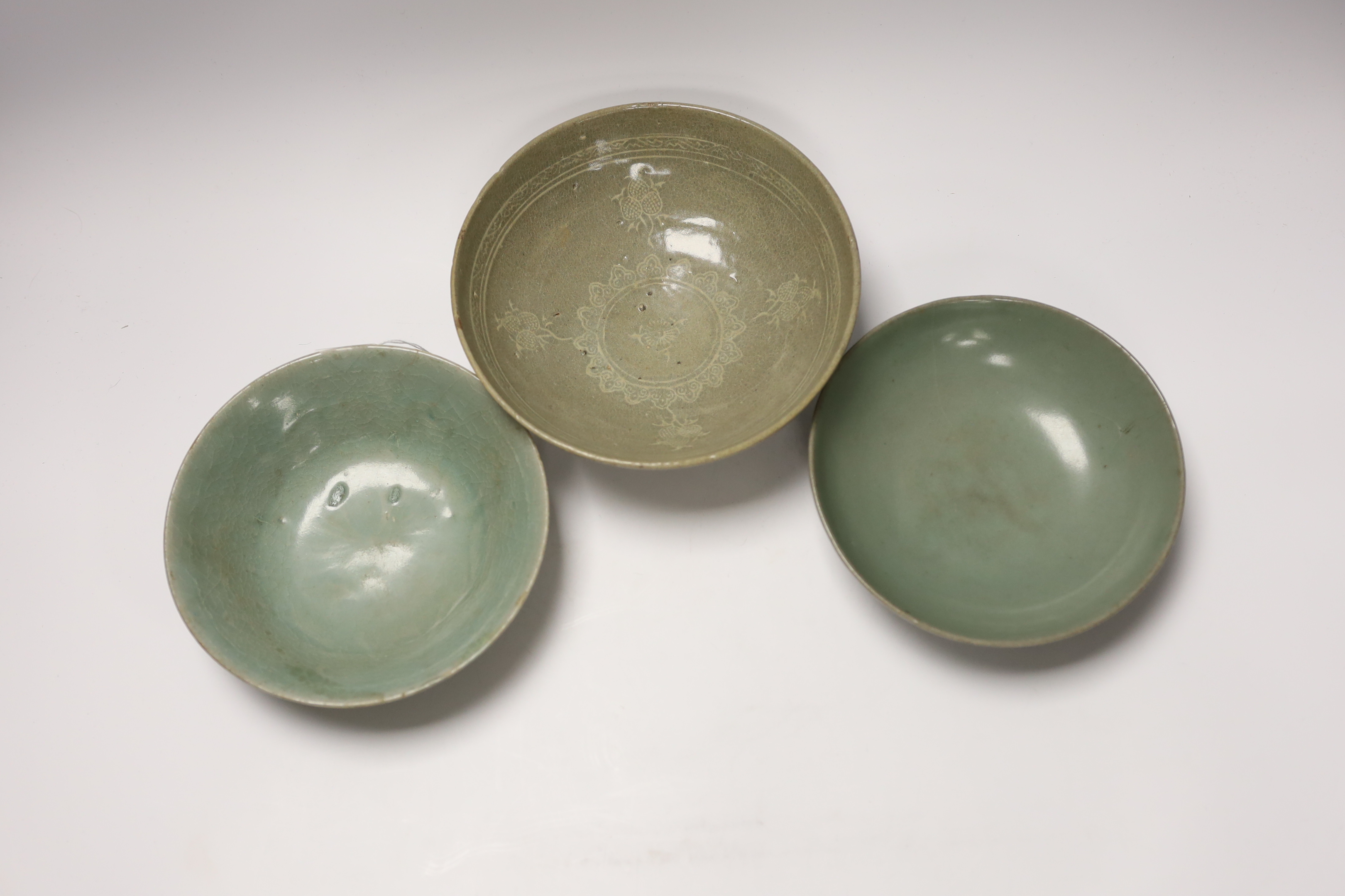 Two Korean celadon bowls, Goryeo dynasty (11th/12th century), the first carved with lotus petals to the underside, the second with fine crackle to the glaze, and a Korean slip-decorated celadon bowl (11th/12th century),